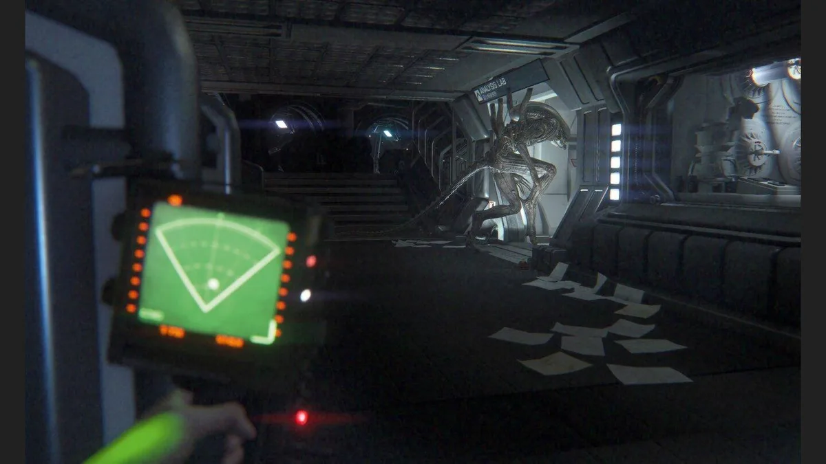 An Alien: Isolation screenshot shows a handheld motion tracker aimed down an industrial corridor.